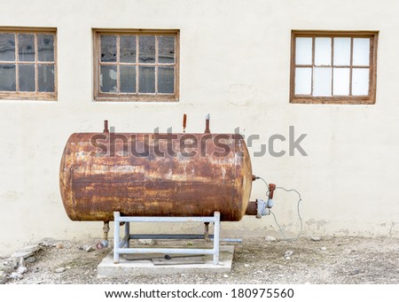 Old rusted propane tank near a building