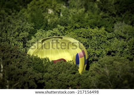 Yellow hot air balloon landing in trees