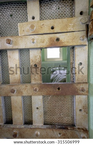Rusted jail cell bars and bed