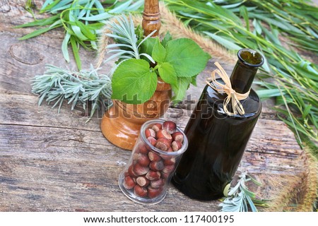 Plants bottle mortar nuts lavender leaves on vintage boards. Making oil