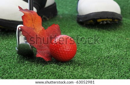 red autumn golf ball with iron and golf shoes