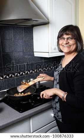 An indian lady in the kitchen making a curry