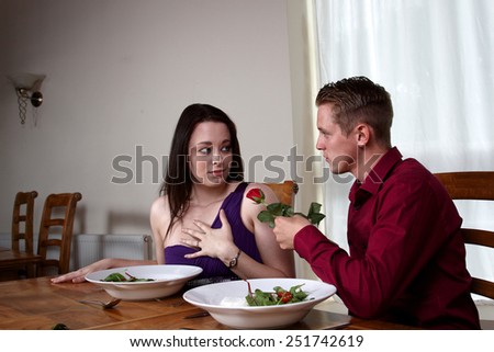A young man handing a red rose to his girlfriend