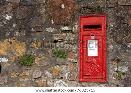 An old red letter box embedded into a stone wall
