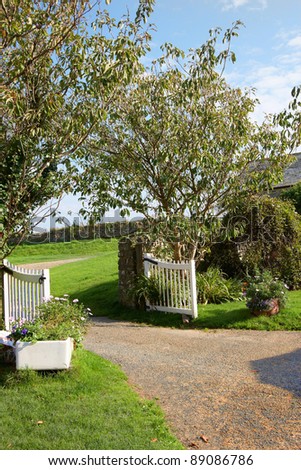 Open gates and driveway into a landscaped garden
