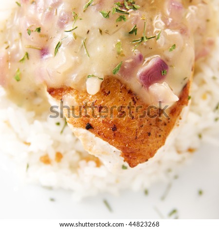 close up shot of chicken breast fillet with lemon thyme sauce served with garlic rice