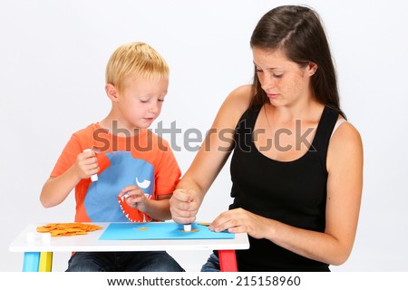 Babysitter and child making a drawing with glue and paper