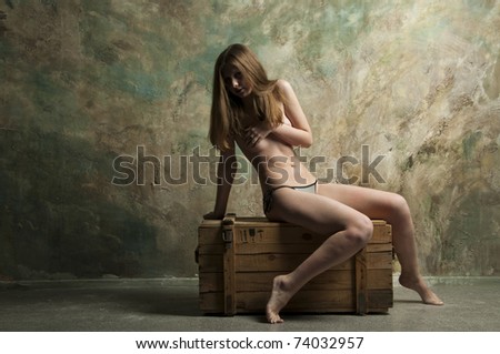 Skinny woman sitting on a wooden chest