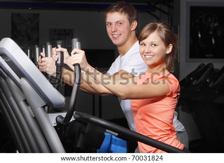 Young couple on exercise bicycle in fitness club