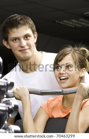 Young beautiful girl and her trainer in fitness club