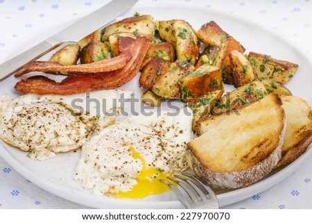 Indulgent breakfast of bacon, potato hashbrowns, sunny side eggs, and sourdough toast.
