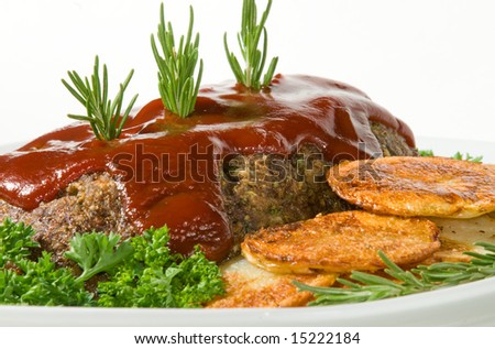 Meatloaf with fresh herbs, tomato sauce, and pan fried potatoes on white serving platter.