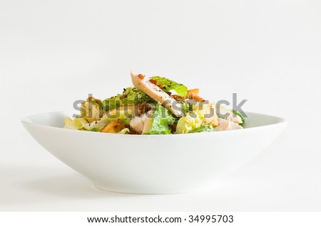 Bowl of chicken Caesar salad, on white