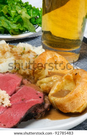 Traditional English Sunday Dinner of Roast Beef, Mashed Potatoes, Gravy, Yorkshire Pudding, Carrots, and salad.