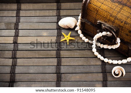 Little chest with treasures and few seashells on a wooden mat.