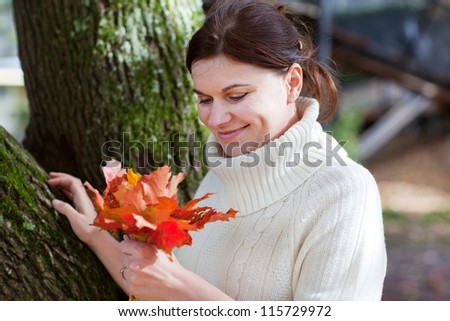 Beautiful young woman in the autumn park collects red and yellow leaves
