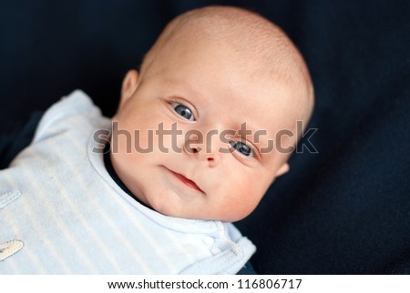 Adorable baby boy with blue eyes two months old on dark blue background