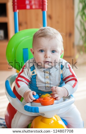Little baby boy playing with toy car indoor in kindergarten