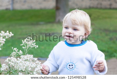 Little cute toddler boy with blond hairs and blue eyes smiling