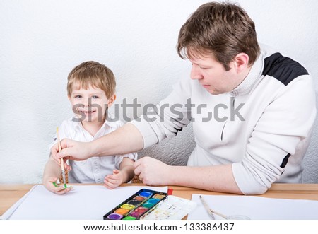 Father and little boy of two years having fun painting at home