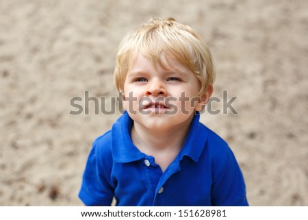 Little cute toddler boy with blond hairs and blue eyes smiling