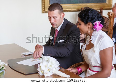 Beautiful indian bride and caucasian groom during wedding ceremony. Selective focus on groom.