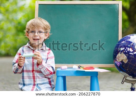 Little boy at blackboard practicing mathematics, outdoor school or nursery. Back to school concept