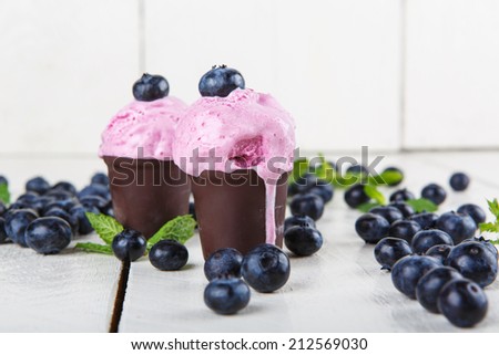 Blueberry ice cream or frozen yogurt in chocolate cup and sprig of mint, with fresh berries