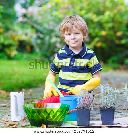 Adorable little blond boy gardening and planting flowers in home\'s garden or farm, on warm sunny day. Outdoors. Environment concept.