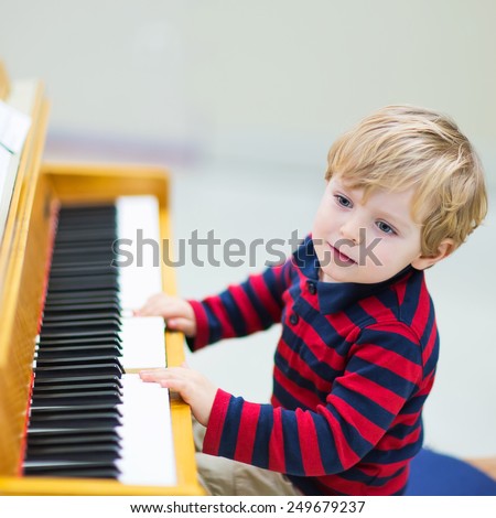 Two years old happy toddler boy playing piano. Early music education for little kids. child at school, learning music instrument.