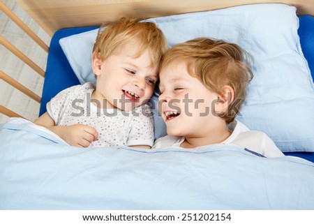 Family of two little boys: Twins having fun in bed at home, indoors.