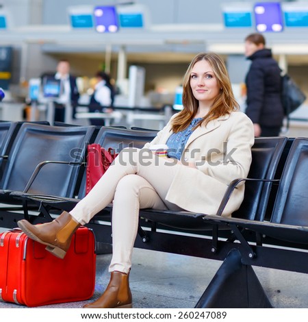 Beautiful woman at international airport sitting and drinking coffee to go while waiting for her flight. Female passenger at terminal, indoors. Traveling people.
