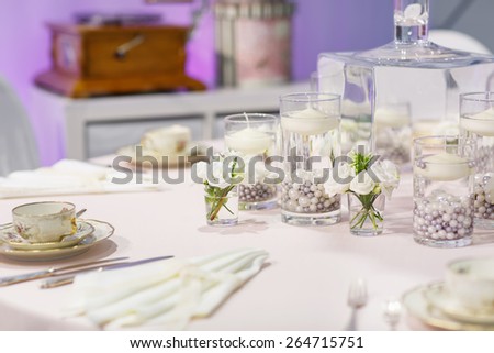 Elegant table set in green and white for wedding or event party, indoor. Flower arrangements, china and porcelain tableware and napkins. Wedding details.