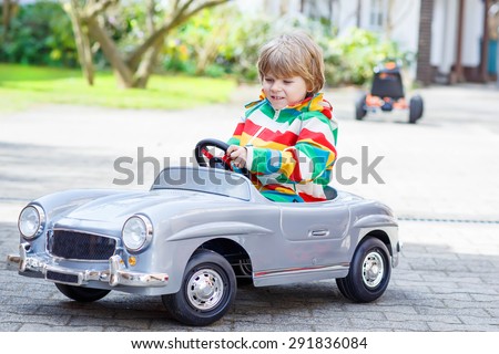 Two happy boys friends playing with big old vintage toy car in spring or autumn garden, outdoors. Active leisure with kids outdoors  on warm spring or autumn day.