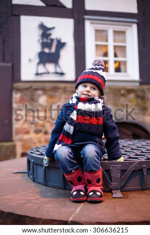 Funny little boy on Christmas funfair or market, outdoors. Happy child having fun. Traditional xmas market in Germany, Europe. Holiday, children, lifestyle concept.
