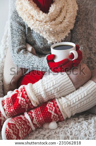Woman sitting on the chair in light room with cup of coffee in hands in christmas,