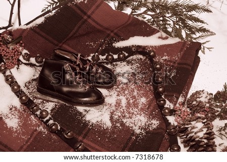 vintage winter holiday concept with old child\'s ice skates, antique sleigh bells, plaid horse blanket, pine cones, berries, & \