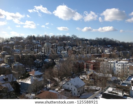 Houses on a hillside beneath blue sky and clouds, suburban Boston
