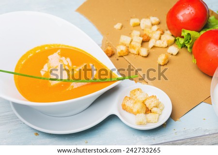 Tomato soup with croutons and shredded cheese on the wooden table