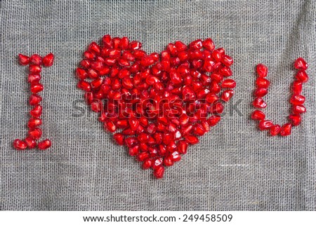the phrase I love you  from pomegranate seeds on a cloth background