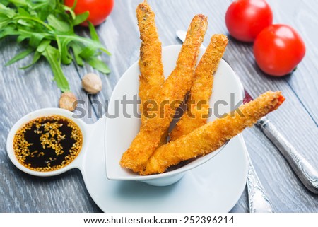 Tempura Shrimps (Deep Fried Shrimps) with sweet sauce on a wooden table with tomatoes and herbs
