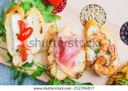 mix of traditional Spanish tapas on a wooden plate with decor, tomatoes and spices