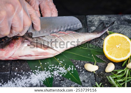 Process of cooking Dorado fish with lemon and herbs hands cook cut up the fish on a stone cutting board