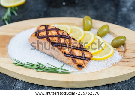 stages of cooking salmon on the grill - cook a delicious salmon fillet grilled served on a wooden plate with olives and lemon sea salt