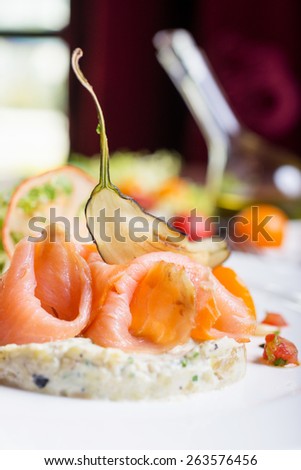 delicious smoked sliced salmon with tartar sauce on a white plate on a wooden table in a restaurant with decor