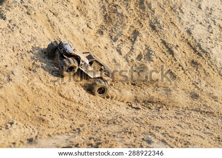 radio controlled monster truck performing a trick at high speed jumps over a large pile of sand. soft focus and beautiful bokeh