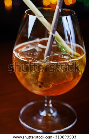 Bright strong alcoholic cocktail with a creative decoration of chocolate sticks and ice cubes on a table in a restaurant with backgrounds of colored disco lights soft focus and beautiful bokeh.