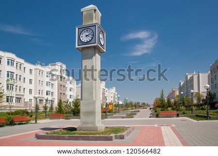 street clock on a stone tower on the background of low buildings