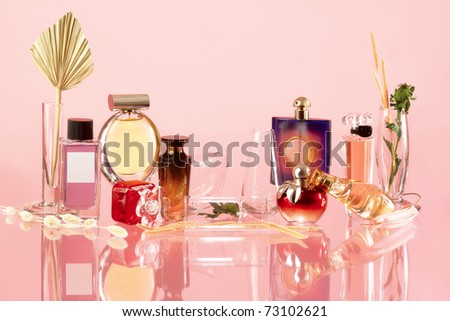 The composition of the various perfume products on a pink background and a true reflection