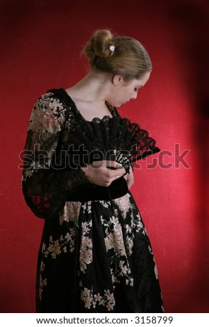 pretty young lady  in old time ball dress with black fan Standing girl with a red fan dress in  style of the beginning of XX century